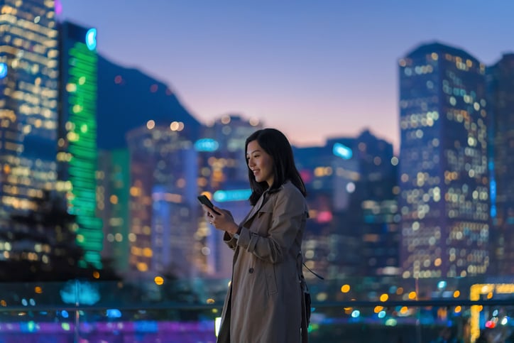 Person on device in front of city.